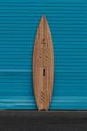 The front of this pointed nose wooden tow board presents cork traction pads made by sustainable surf brand Nomads Surfing, as well as a strap insert below the top traction pad.